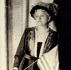 Image description: A black-and-white photo of Carrie Chapman Catt holding an American flag.