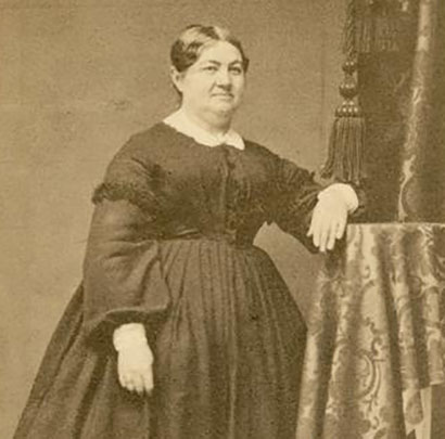 Image description: A black-and-white photo of Elizabeth Baird leaning against a table.