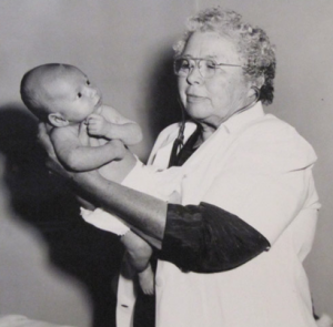Image description: A black-and-white photo of Kate Newcomb holding an infant.